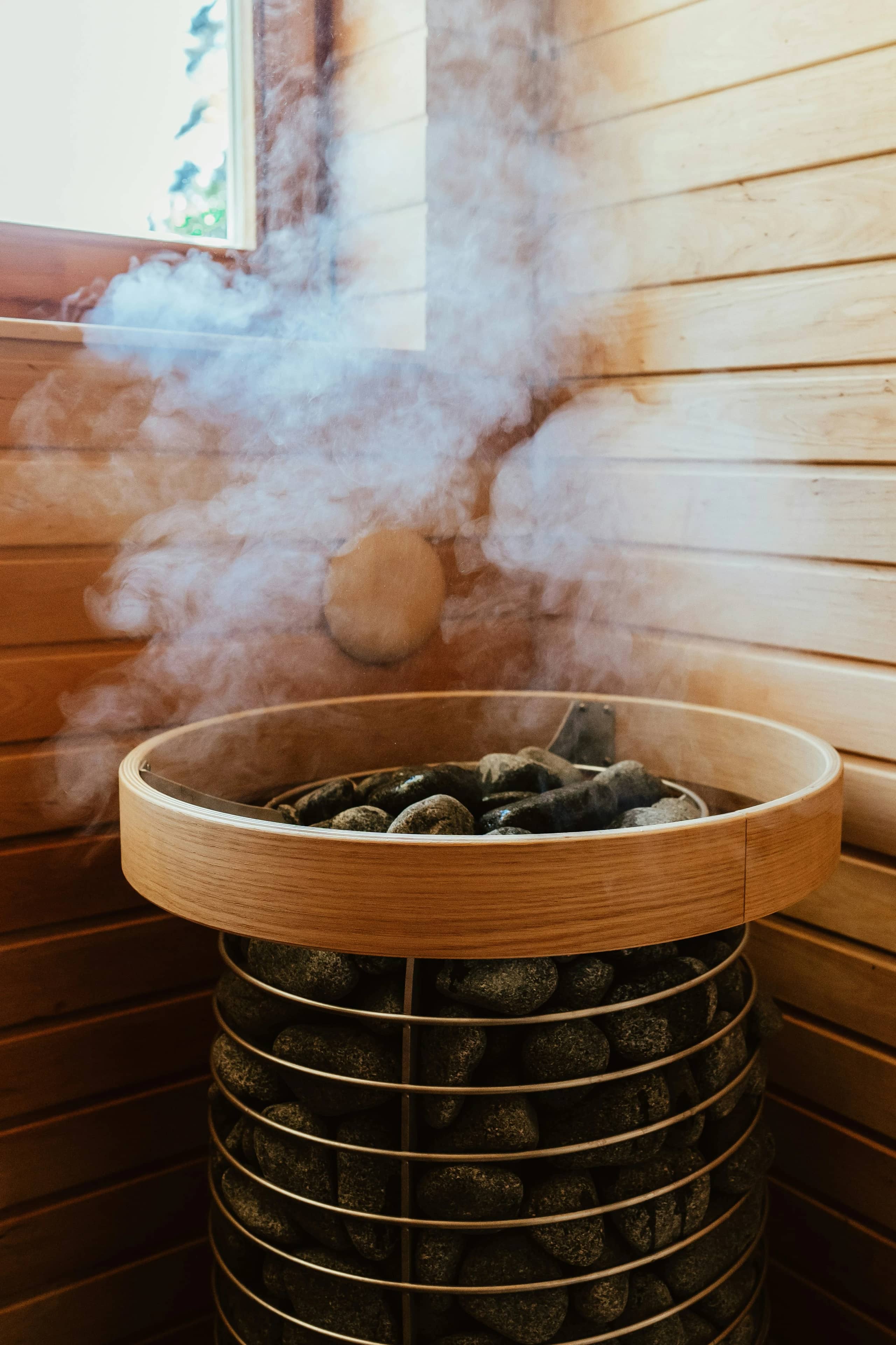 Steam rising off hot sauna rocks in a traditional Finnish sauna